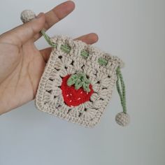 a hand holding a small crocheted bag with a strawberries motif on it