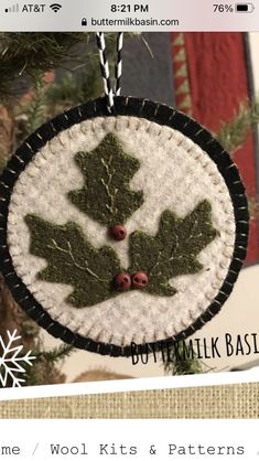 an ornament hanging from a christmas tree decorated with green leaves and red berries