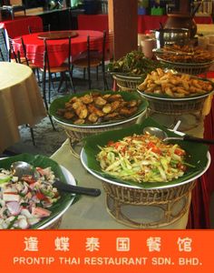 a table topped with lots of different types of food next to tables covered in red cloths