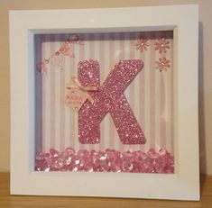 the letter k is made out of pink and white paper with some glitter on it