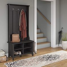 an entryway with a bench, coat rack and rug on the floor next to it