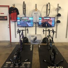 two bikes are sitting on mats in front of televisions and video games at the same time