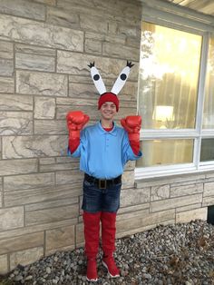 a person wearing red boxing gloves standing in front of a brick building with two fists up