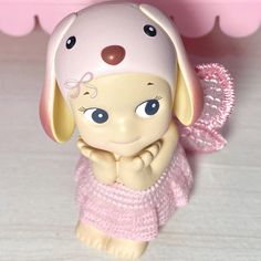 a small toy dog wearing a pink dress and holding its paw up to the side