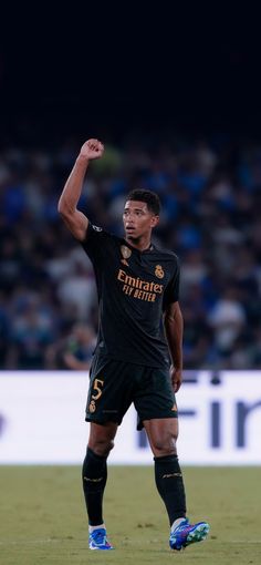 a man standing on top of a field holding a soccer ball in his hand and raising his fist