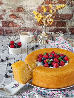 a cake on a plate with berries and blueberries in the middle next to it