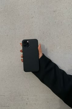 a person holding an iphone case in their left hand on the concrete floor, looking down at it