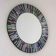 a circular mirror with multicolored strips hanging on the wall next to a white wall