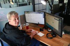 a man sitting in front of two computer monitors