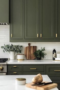 a kitchen with green cabinets and white counter tops