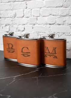 two leather flasks sitting on top of a table next to a brick wall