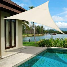 an outdoor swimming pool with a shade sail over it's head and water in the background