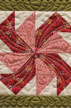 a red and white quilted wall hanging with an intricate design on the center piece