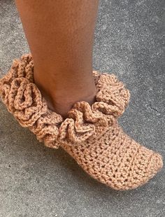 a close up of a person's feet wearing crocheted slippers with ruffles