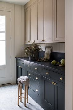 a kitchen with white cabinets and black counter tops, two stools in the foreground