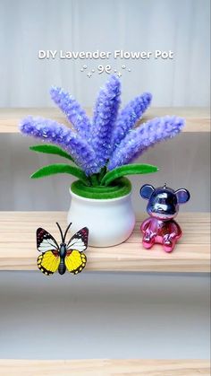 purple flowers in a white vase with a small toy animal next to it on a shelf