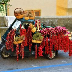 a car with baskets on the roof filled with chili peppers and other produce hanging from it's roof