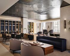 a living room filled with lots of furniture next to a tall wall covered in bookshelves