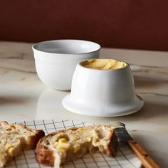 two pieces of bread sitting on top of a counter next to a bowl and knife