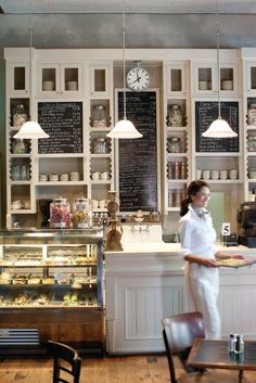 a bakery with chalkboard menus on the wall and shelves filled with pastries