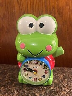 a green frog clock sitting on top of a counter