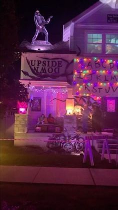 a house decorated for halloween with lights and decorations on the front porch, including a sign that says upside down