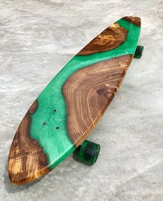 a wooden skateboard with green and brown wood on it's side sitting on concrete