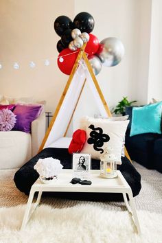 a living room filled with balloons and decorations on top of a white table in front of a couch