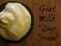 a bowl filled with cream sitting on top of a wooden table next to a sign that says goat milk sour cream