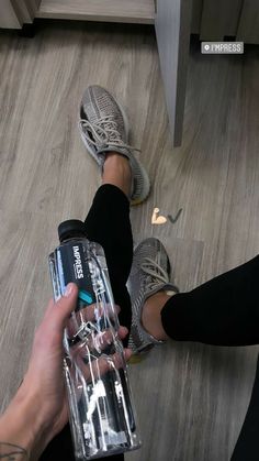 two people standing on the floor with their feet up and one holding a water bottle