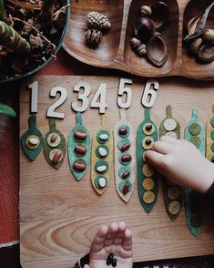 a child is playing with numbers and shapes on a wooden board in front of pine cones