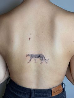 the back of a woman's body with a cat tattoo on it