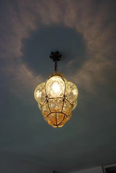 a light fixture hanging from the ceiling with clouds in the sky behind it on a cloudy day