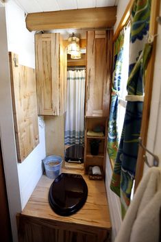 a small bathroom with wooden cabinets and a black bowl on the counter top in front of it