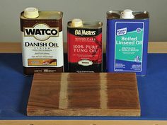 three different types of wood are sitting on a blue table cloth next to two cans of oil