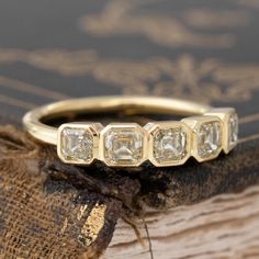 three stone ring sitting on top of a piece of wood next to an old book