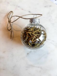 a glass ornament filled with dried herbs on top of a marble countertop