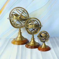 three antique brass globes sitting on top of each other in front of a blue and white background