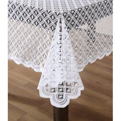 a white table cloth on top of a wooden table with an intricate design and lace