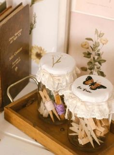 two jars with clothes pins in them on a wooden tray