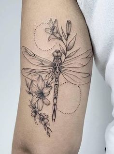 a woman's thigh with flowers and a dragonfly tattoo on the side of her leg