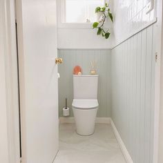 a white toilet sitting inside of a bathroom next to a window on the side of a wall