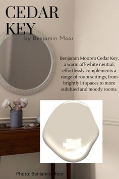 a white bathroom with a round mirror on the wall and an advertisement for cedar key by benjamin moore's cedar key