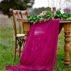 the table is covered with a pink blanket and flowers on it, along with two wooden chairs