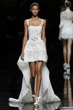 a model walks down the runway in a white dress