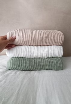 a person is holding three folded towels on top of each other in their hand,