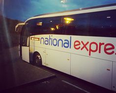 the national express bus is parked on the side of the road at night with it's lights on