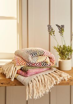 three blankets stacked on top of each other next to a potted plant