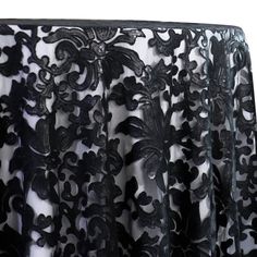 black lace curtain with flowers and leaves on the bottom, in front of a white background