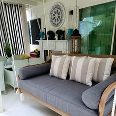 a couch with four pillows on it in front of a mirror and window sill